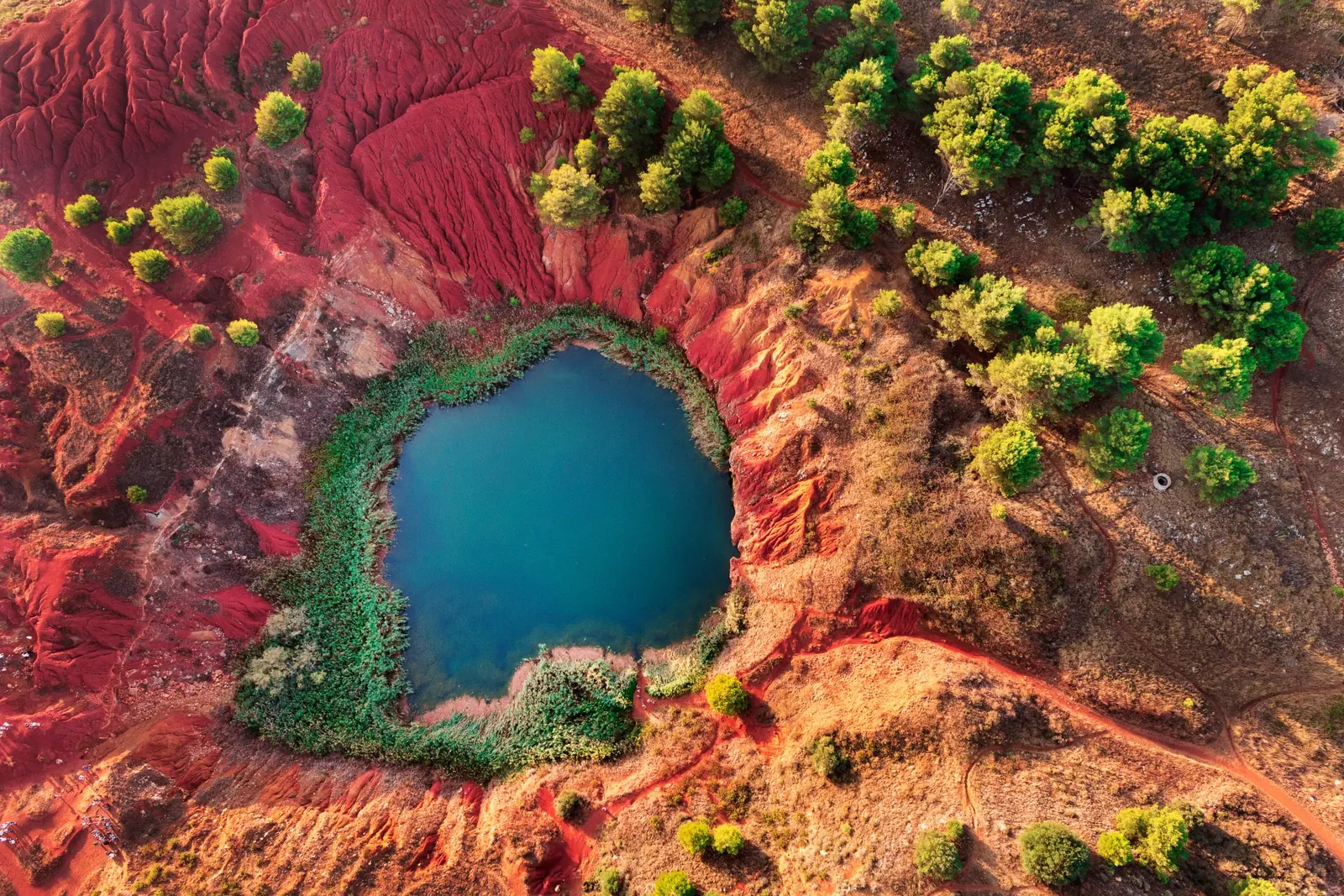 Scenic Bauxite quarries near Otranto in Puglia, Italy, with striking red rocks, emerald green lake, and unique natural landscape